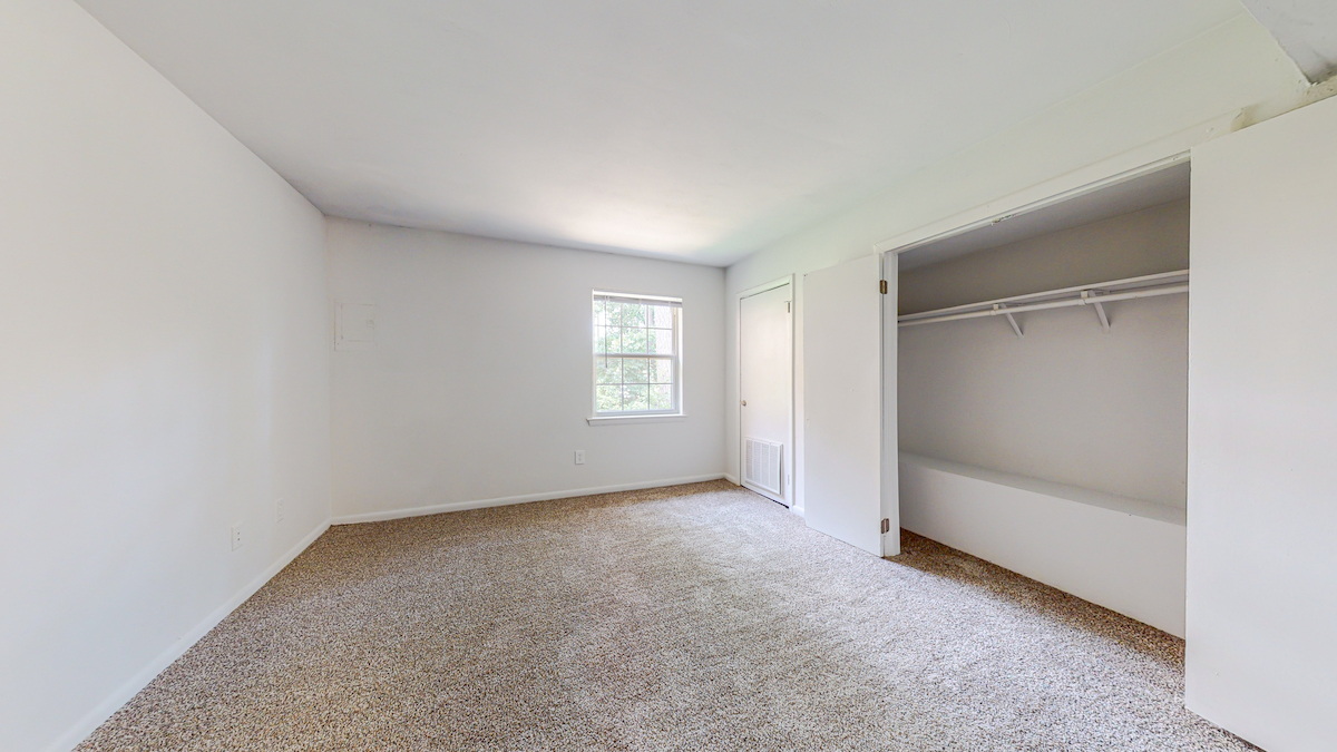 Carpeted bedroom with window and closet