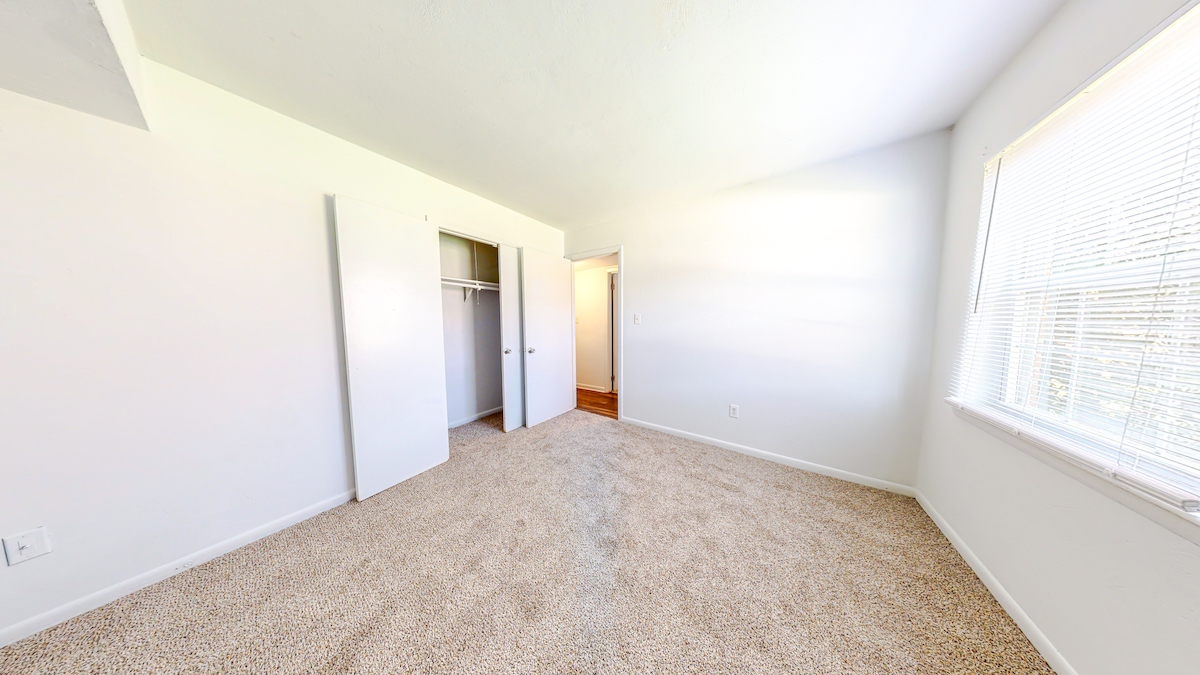 Carpeted room with bright window and closet